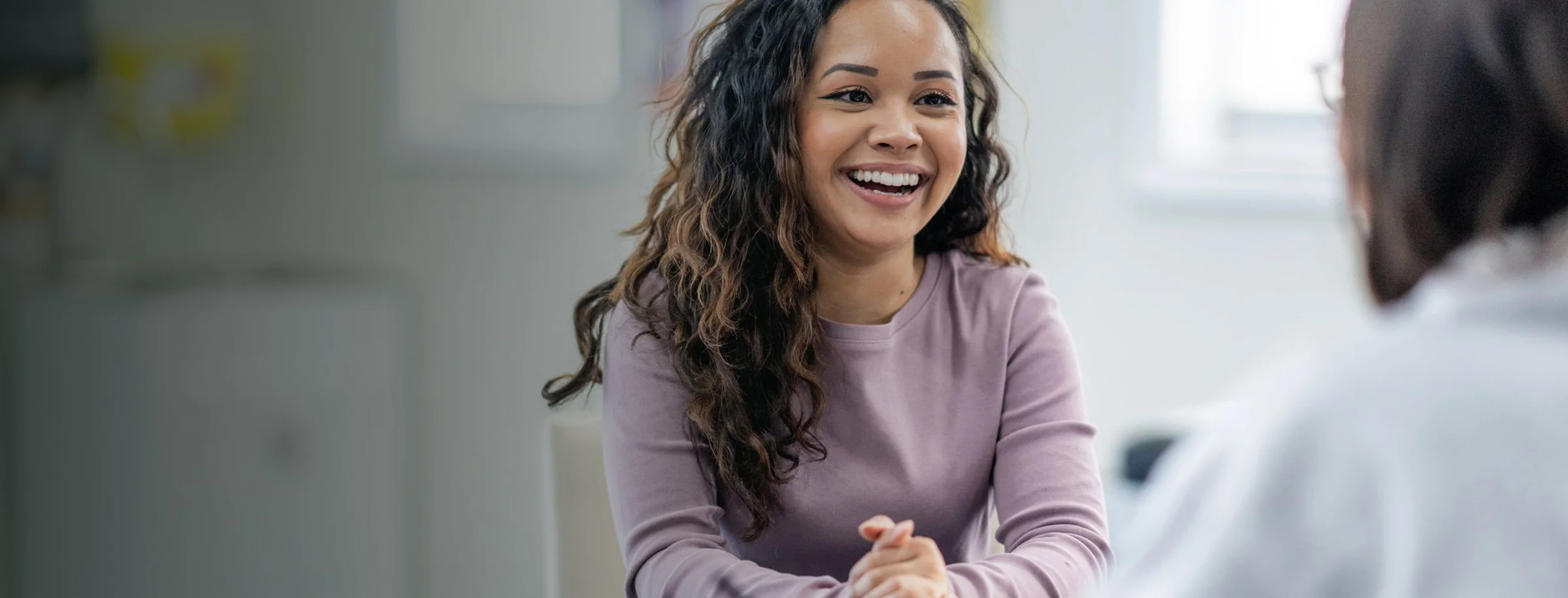 Two colleagues talking and laughing across a desk