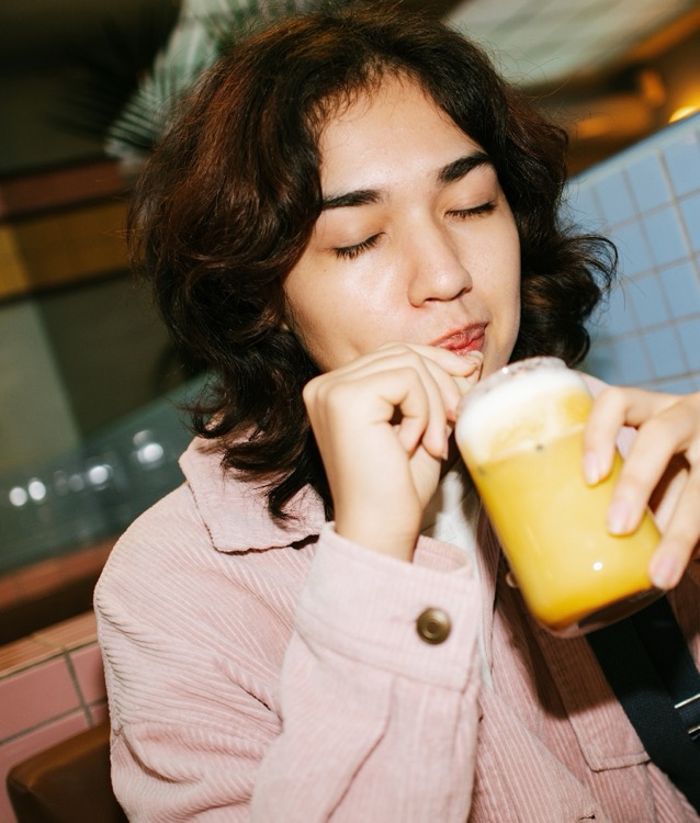 A person sipping a drink through a straw in a tiled café